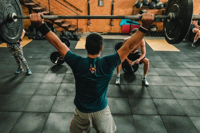 Homme en t-shirt noir lève une barre de poids avec ses mains